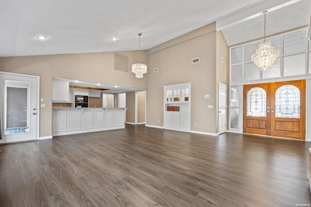 unfurnished living room with a chandelier, high vaulted ceiling, visible vents, baseboards, and dark wood finished floors