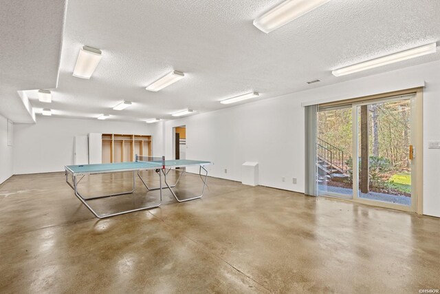 recreation room with finished concrete flooring, visible vents, and a textured ceiling