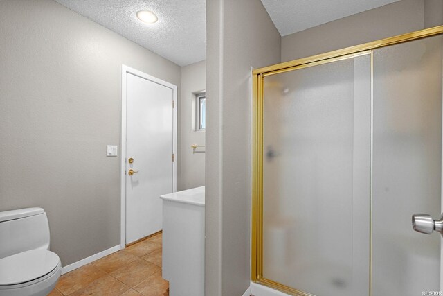 full bath with a textured ceiling, toilet, baseboards, a shower stall, and tile patterned floors