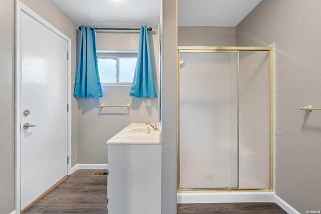 bathroom with baseboards, wood finished floors, vanity, and a shower stall