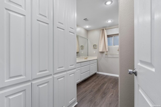 bathroom featuring visible vents, baseboards, wood finished floors, vanity, and a closet