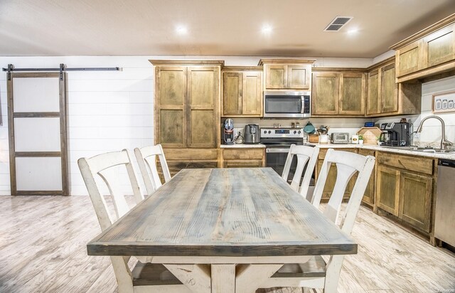 kitchen with a barn door, a sink, visible vents, light countertops, and appliances with stainless steel finishes