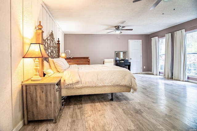 bedroom with access to exterior, a textured ceiling, visible vents, and wood finished floors