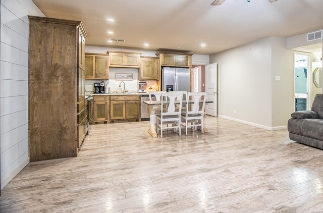 kitchen featuring light countertops, light wood-style floors, open floor plan, a sink, and stainless steel fridge