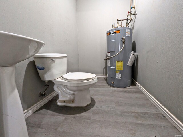 half bath featuring baseboards, electric water heater, toilet, and wood finished floors