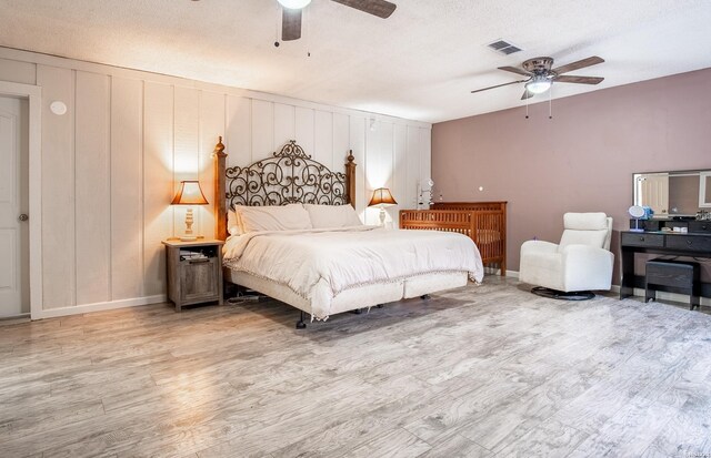 bedroom with baseboards, visible vents, ceiling fan, and light wood finished floors