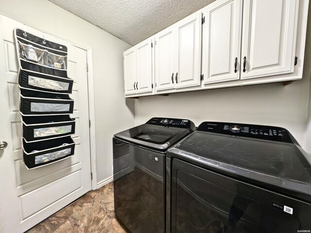 clothes washing area with baseboards, cabinet space, washer and clothes dryer, and a textured ceiling