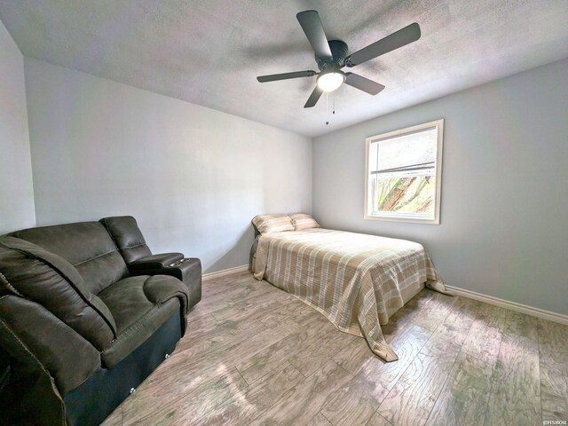 bedroom with baseboards, a textured ceiling, and light wood finished floors