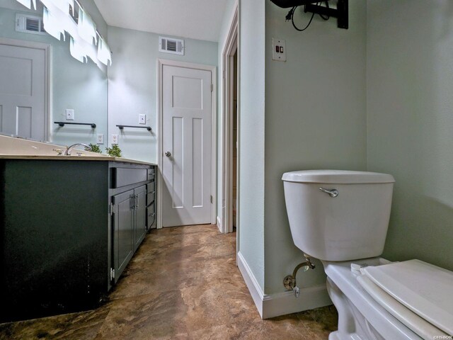 half bathroom featuring baseboards, visible vents, vanity, and toilet