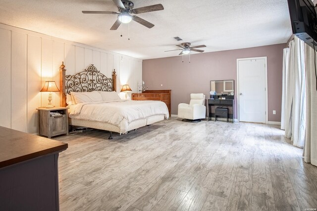 bedroom featuring a textured ceiling, ceiling fan, wood finished floors, and visible vents