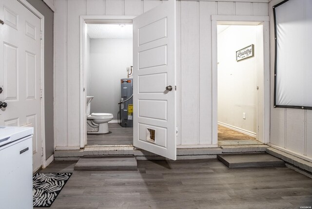 bathroom with baseboards, water heater, toilet, and wood finished floors