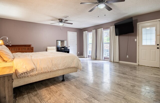 bedroom featuring a textured ceiling, wood finished floors, a ceiling fan, visible vents, and baseboards