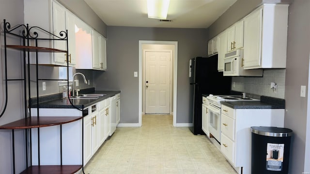 kitchen with white appliances, visible vents, dark countertops, white cabinetry, and a sink