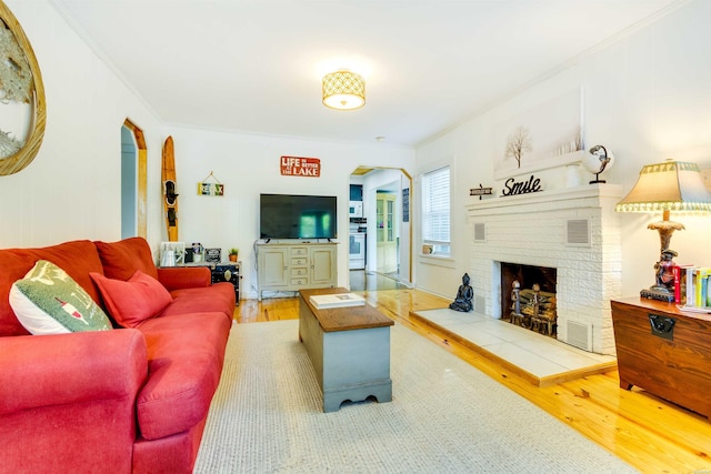 living area with visible vents, arched walkways, ornamental molding, and wood finished floors