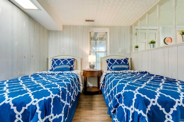 bedroom featuring wooden walls, visible vents, and wood finished floors