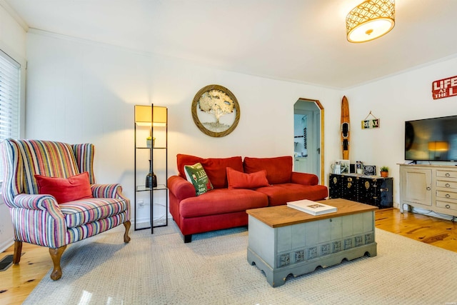 living room featuring arched walkways, wood finished floors, and ornamental molding