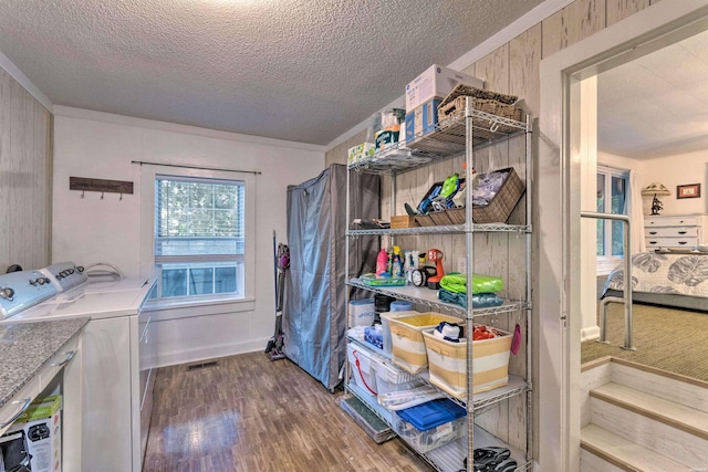 washroom with wooden walls, a textured ceiling, wood finished floors, and laundry area