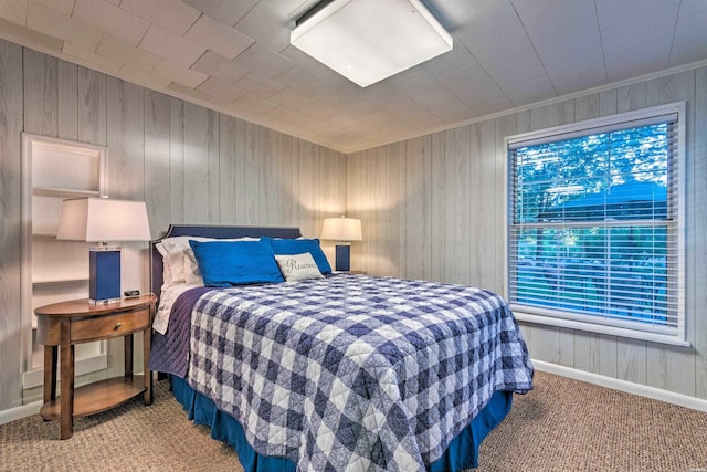 bedroom featuring baseboards, wooden walls, carpet floors, and ornamental molding