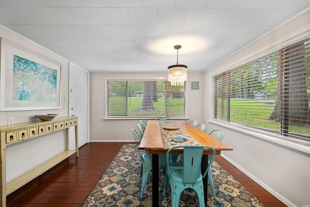 dining room featuring a wealth of natural light, a notable chandelier, brick floor, and baseboards