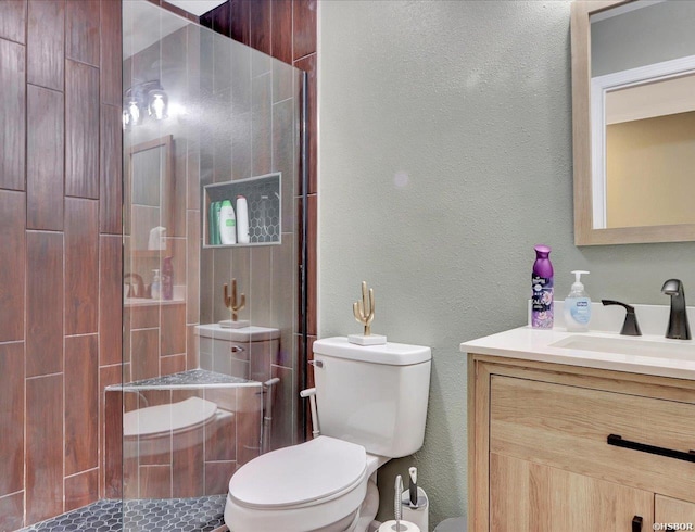 bathroom with a stall shower, a textured wall, vanity, and toilet