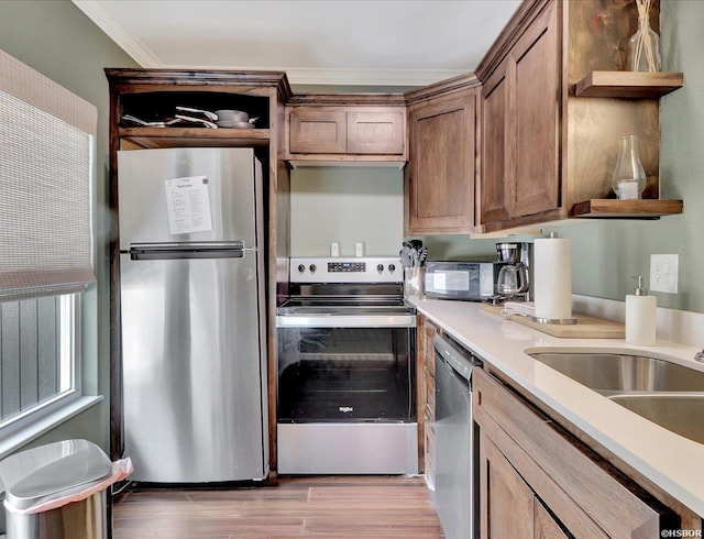 kitchen with appliances with stainless steel finishes, light countertops, crown molding, light wood-style floors, and open shelves