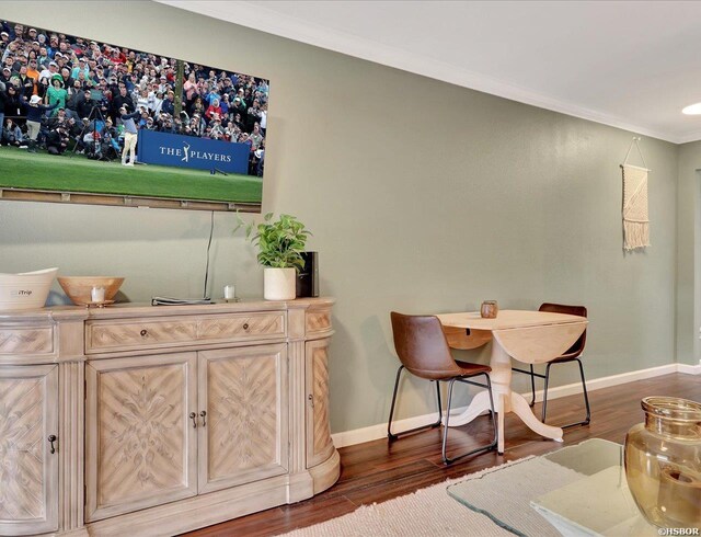 dining area with dark wood-style flooring, crown molding, and baseboards