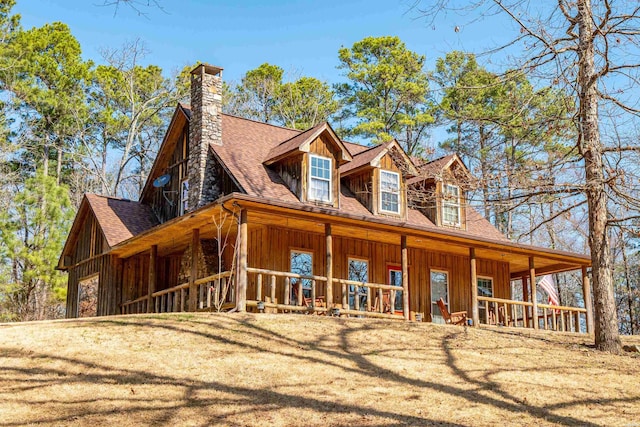 view of front of home with a shingled roof, covered porch, a chimney, and board and batten siding