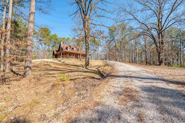 view of road featuring gravel driveway and a wooded view