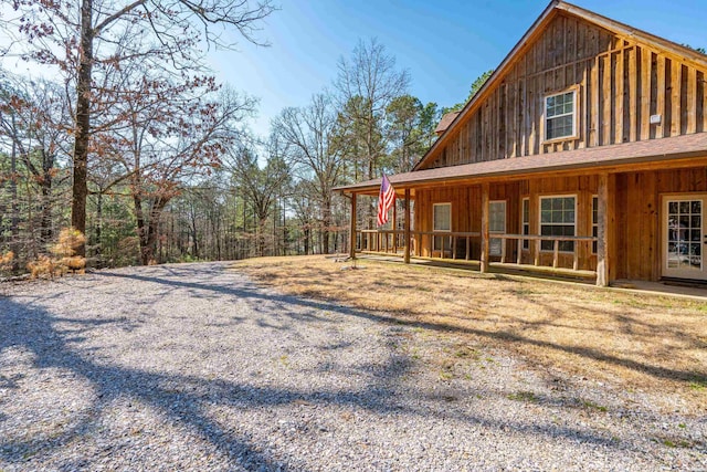 view of property exterior featuring a shingled roof, covered porch, and board and batten siding