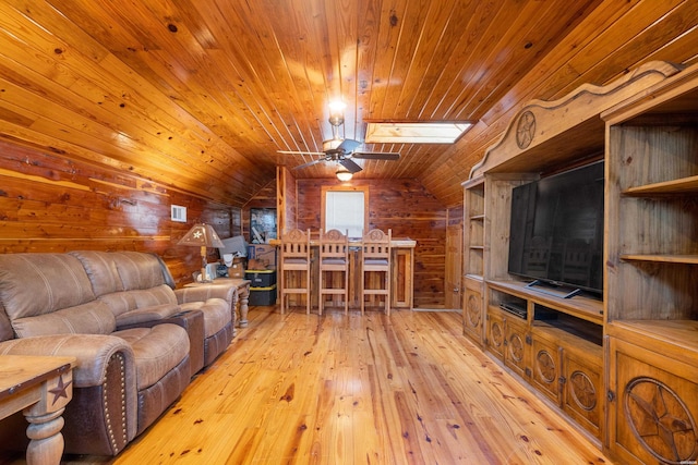 living room with vaulted ceiling with skylight, hardwood / wood-style floors, wood walls, and wood ceiling