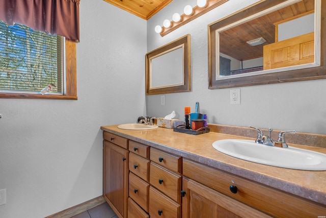 bathroom with double vanity, tile patterned flooring, a sink, and baseboards