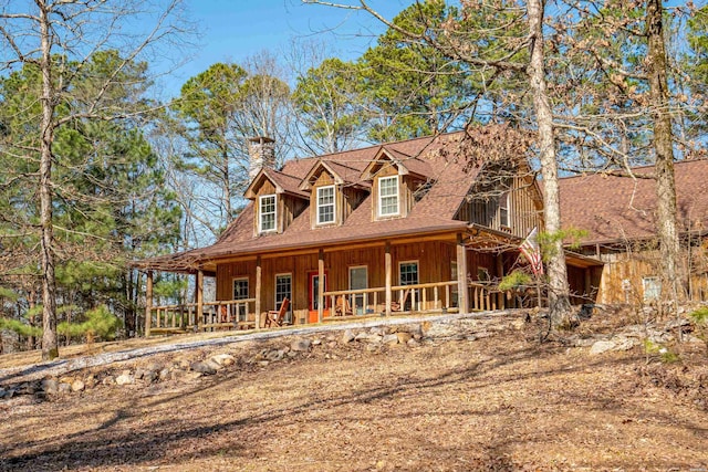 view of front of property with a chimney, a porch, and roof with shingles