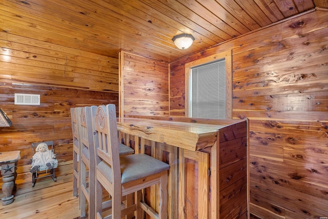 dining space with wood ceiling, wood walls, wood finished floors, and visible vents