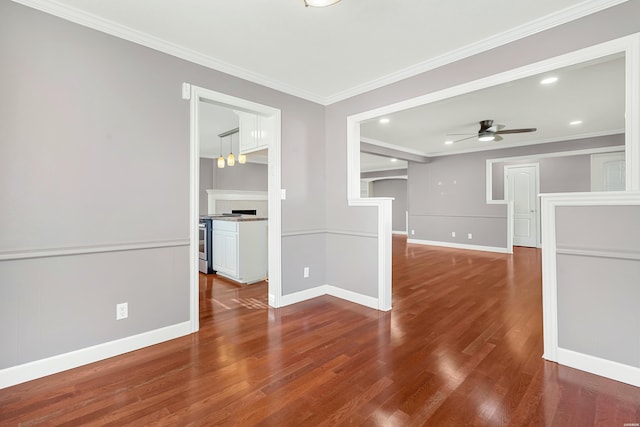 spare room featuring ornamental molding, wood finished floors, a ceiling fan, and baseboards