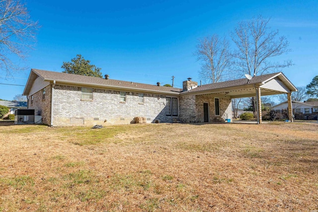 rear view of house with a yard, brick siding, crawl space, and a chimney