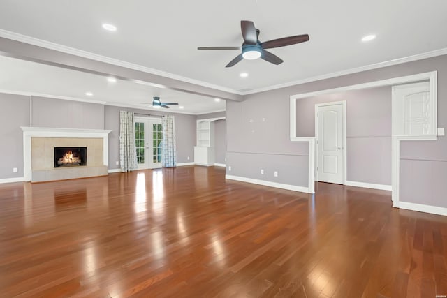 unfurnished living room with ornamental molding, french doors, wood finished floors, and a tile fireplace