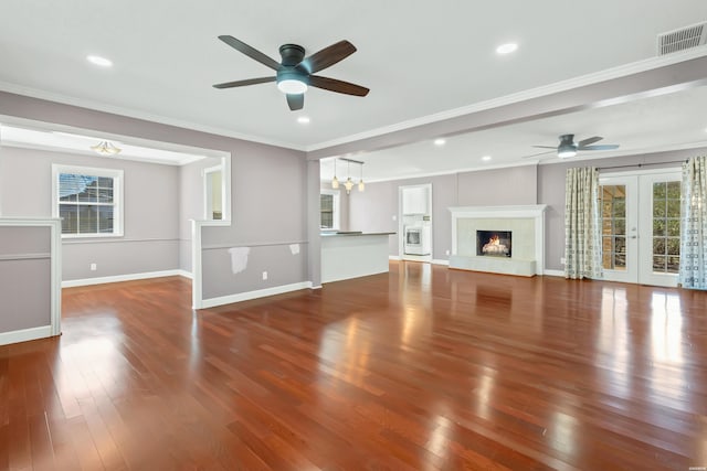 unfurnished living room featuring baseboards, visible vents, wood finished floors, crown molding, and french doors