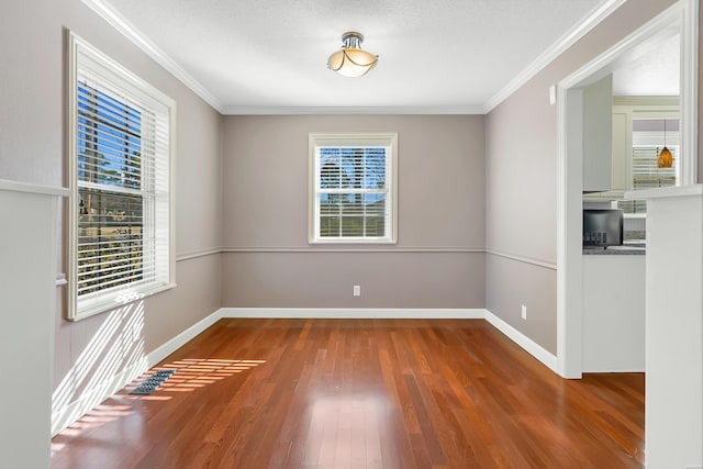 empty room featuring crown molding, baseboards, and wood finished floors