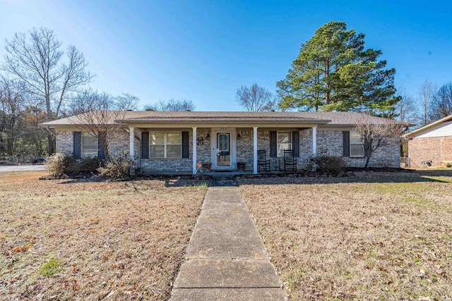 ranch-style house featuring a porch, a front yard, and brick siding