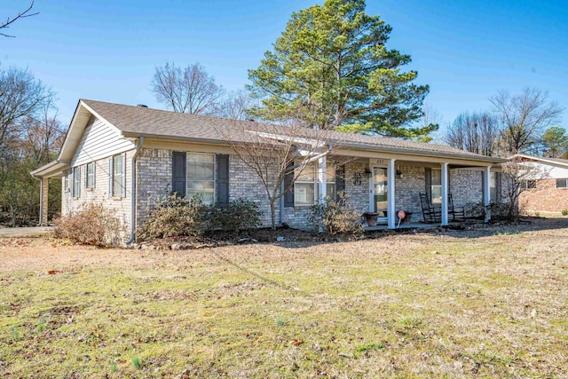 single story home featuring brick siding, a porch, and a front yard