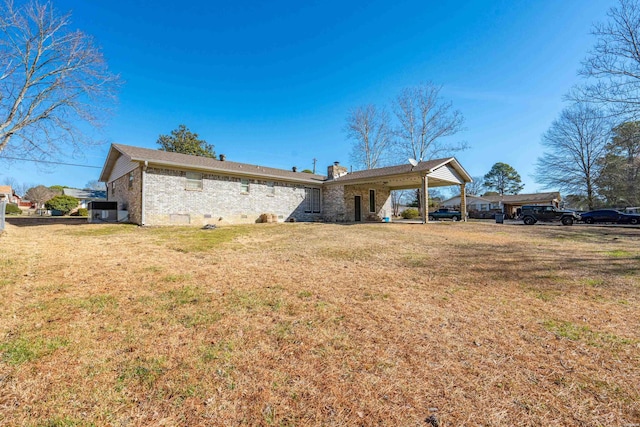 back of property with crawl space, brick siding, a chimney, and a yard