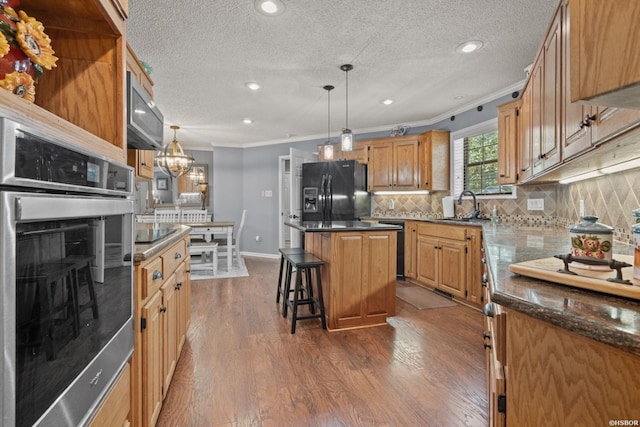 kitchen with tasteful backsplash, dark wood-type flooring, crown molding, black appliances, and a sink