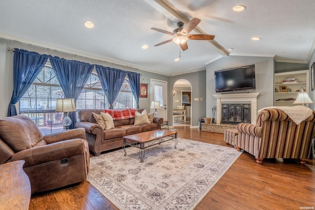 living room with vaulted ceiling with beams, arched walkways, a textured ceiling, and wood finished floors