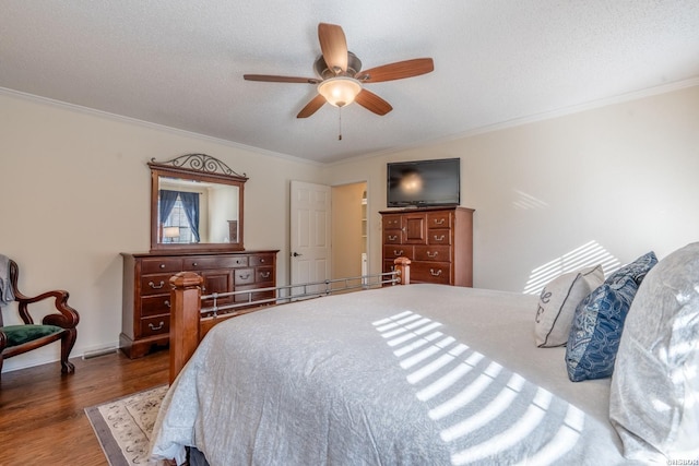 bedroom with baseboards, a ceiling fan, ornamental molding, wood finished floors, and a textured ceiling