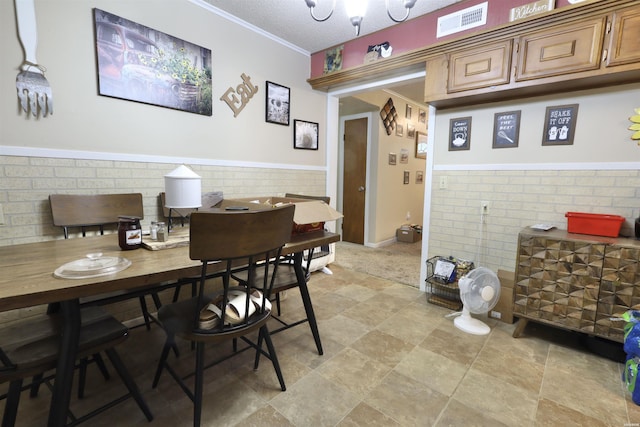 dining space featuring a textured ceiling, wainscoting, visible vents, and crown molding