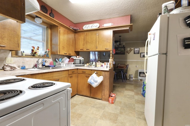 kitchen with light countertops, white appliances, a sink, and brown cabinets