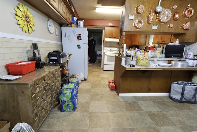 kitchen featuring light countertops, brown cabinetry, a peninsula, white appliances, and under cabinet range hood