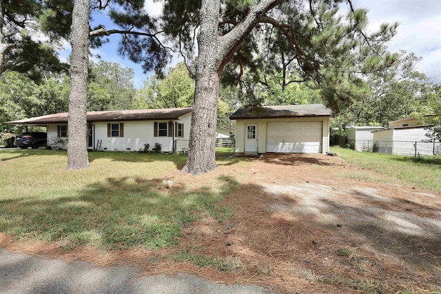 back of property with an outbuilding, a detached garage, fence, a yard, and crawl space