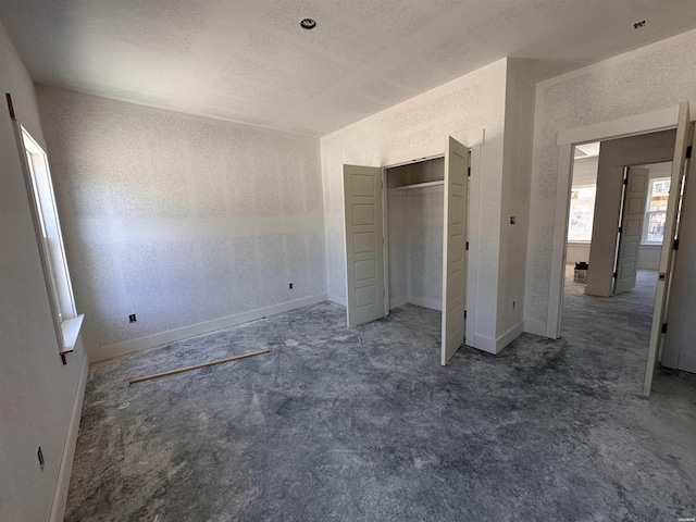 unfurnished bedroom with carpet flooring, baseboards, a closet, and a textured wall