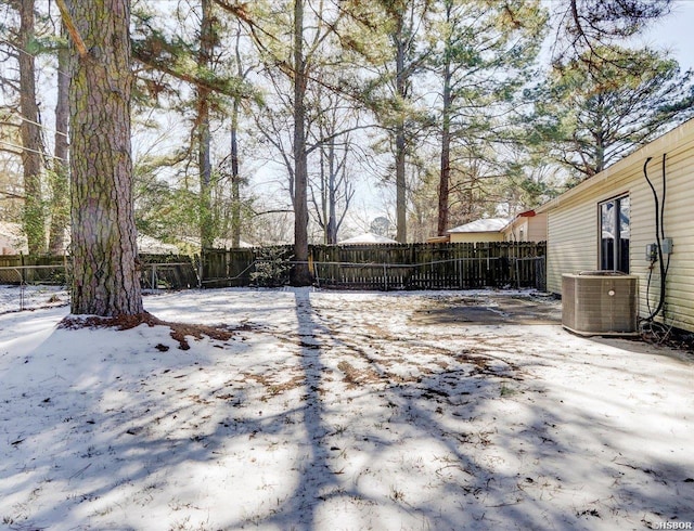 yard covered in snow featuring a fenced backyard and central AC unit